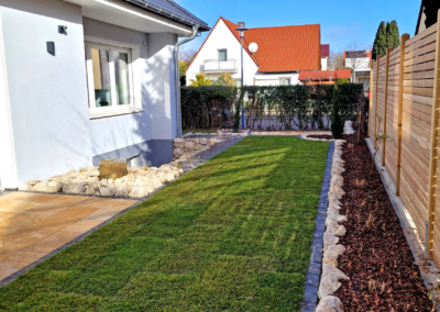 Privatgartengestaltung mit Terrasse, Natursteinelementen und Zaunbau